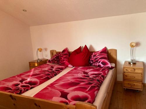 a large bed with red sheets and pillows at Sissy Appartment in Kössen