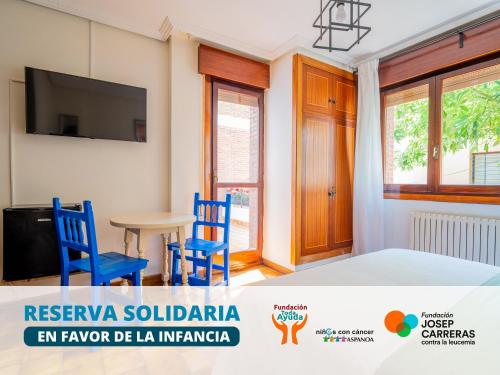 a room with two blue chairs and a table and a tv at Oliva Rooms 3000 in Santander