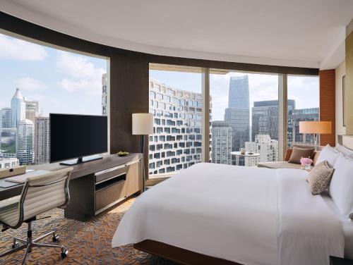 a hotel room with a bed and a desk and a large window at The Langham, Shanghai, Xintiandi in Shanghai