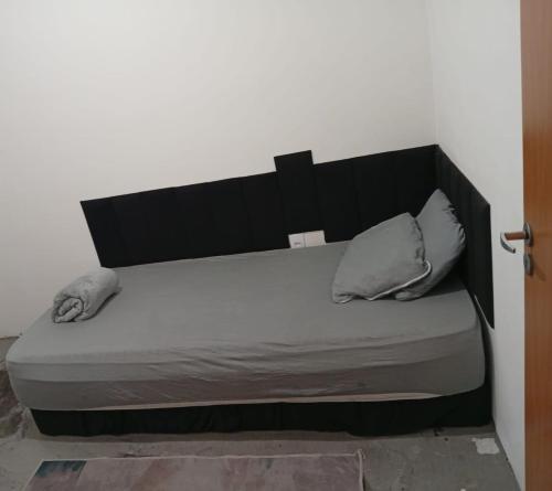 a bed with a black headboard and two pillows at Apartamento Serena in Votorantim