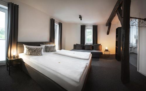 ein Schlafzimmer mit einem großen weißen Bett und einer Couch in der Unterkunft Hotel Apartment Ferienwohnung Meyenhof Frankenberg Eder in Frankenberg