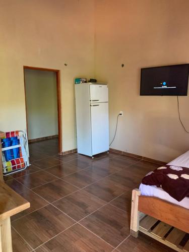 een kamer met een koelkast en een tv aan de muur bij Cabañas la flor 