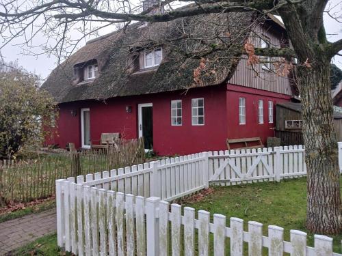 une maison rouge avec une clôture blanche devant elle dans l'établissement Haus Bei Der Kirche, à Oland