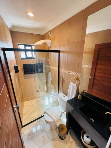 a bathroom with a toilet and a glass shower at Residence Pipa Beach in Pipa