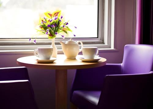 een tafel met twee kopjes en een vaas met bloemen erop bij Tor Park Hotel in Torquay