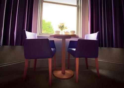 a table and chairs in a room with a window at Tor Park Hotel in Torquay