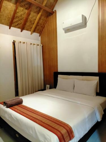 a bedroom with a large white bed with a light at Tania Homestay in Bumbang