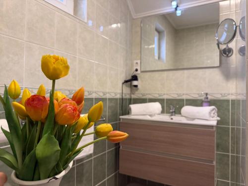 a bathroom with a vase with yellow flowers in it at Amfora Panzió in Gyula
