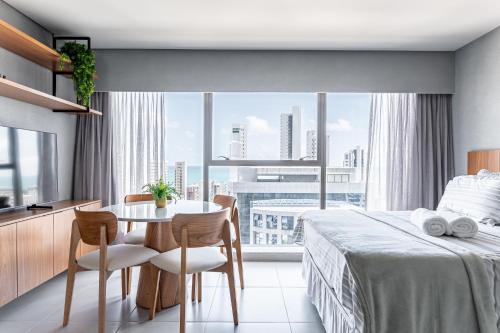 een slaapkamer met een bed en een tafel en een groot raam bij ICON - Vista Mar Boa Viagem in Recife