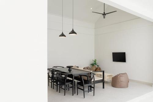 a dining room with white walls and a black table and chairs at Villa IKIN in Lovina