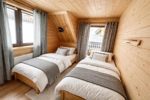 2 letti in una camera con pareti e finestre in legno di Góralska Chatka jacuzzi i sauna a Kościelisko