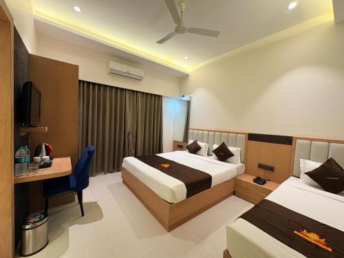 a hotel room with two beds and a desk at Hotel JK Palace Newly Renovate in Shirdi