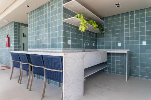 een keuken met blauwe tegelwanden en een aanrecht met blauwe stoelen bij ICON - Vista Mar Boa Viagem in Recife