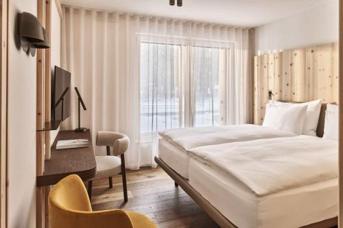 a bedroom with a bed and a desk and a window at The Suites in St. Moritz