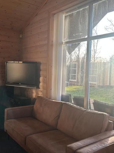 een woonkamer met een bank en een groot raam bij Holmfoss Hytta in Larvik