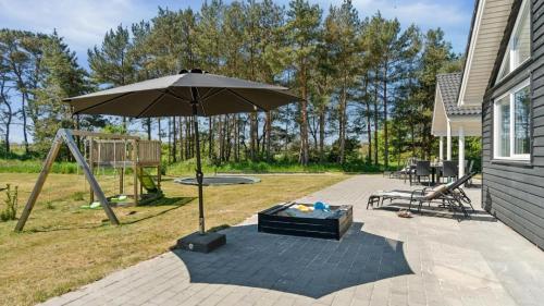 eine Terrasse mit einem Sonnenschirm und einem Spielplatz in der Unterkunft Villavilla #449 - Dueodde, Bornholm in Bedegård