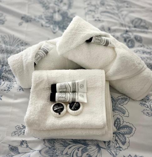 a white towel with two rolls of toiletries on a bed at Village Cottage Marple in Marple