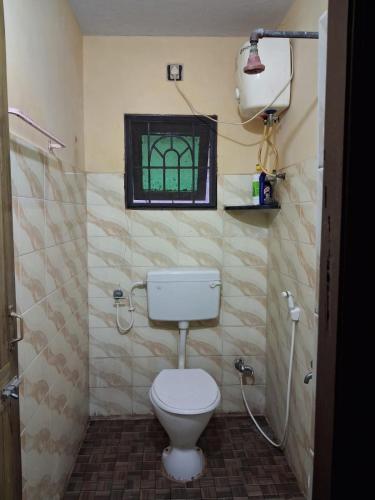 a bathroom with a toilet and a window at MSVNATIVE HOME Stay Near Airport in Chennai