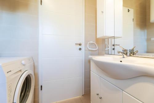 ein weißes Badezimmer mit einem Waschbecken und einer Waschmaschine in der Unterkunft Pansion Burin in Baška