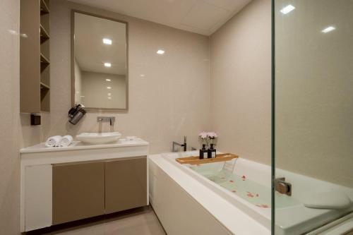 een badkamer met een bad, een wastafel en een spiegel bij 2BR2BA BTS Thonglor Rooftop Pool Gym BBQ Low in Bangkok