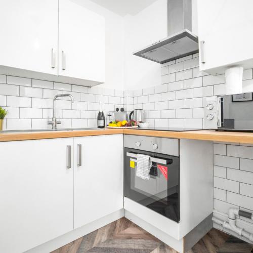 een keuken met witte kasten en een fornuis bij Cozy Apartment - Wolverhampton City Centre - Netflix 12AC in Wolverhampton