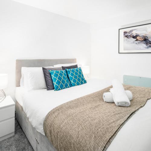een witte slaapkamer met een groot bed met blauwe kussens bij Cozy Apartment - Wolverhampton City Centre - Netflix 12AC in Wolverhampton