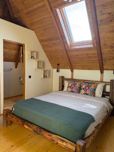a bedroom with a large bed with a skylight at Clop&Cojoc Rustic old wooden house in Bocicoiel