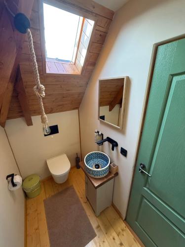 a bathroom with a sink and a toilet and a window at Clop&Cojoc Rustic old wooden house in Bocicoiel