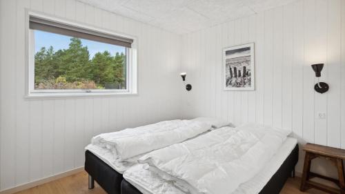 een bed in een witte kamer met een raam bij Villavilla #910 - Marielyst, Lollandfalstermøn in Stovby