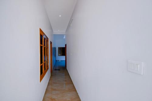 a hallway with white walls and a hallway with a painting at HOTEL O SAV INN in Bhauli