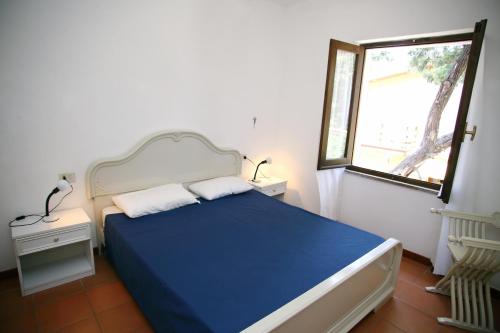 a bedroom with a blue bed and a window at Dimore Dell'Isola Rossa in Isola Rossa
