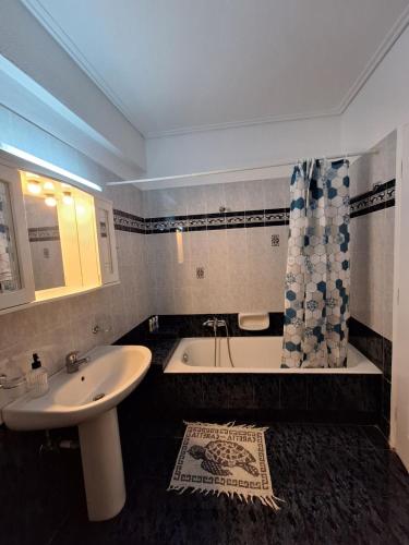 een badkamer met een wastafel, een bad en een douche bij 4youAPARTMENT in Tríkala