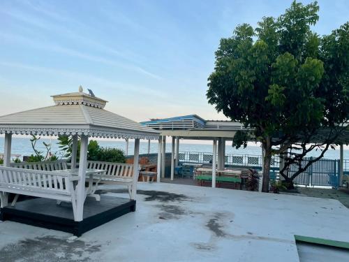 een wit paviljoen met een bank en een boom bij Sea Side Villa in Ban Pak Khlong Cha-am