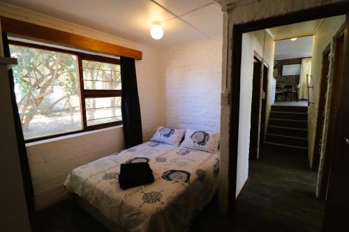 een slaapkamer met een bed met een tas erop bij Shalom House in Arniston