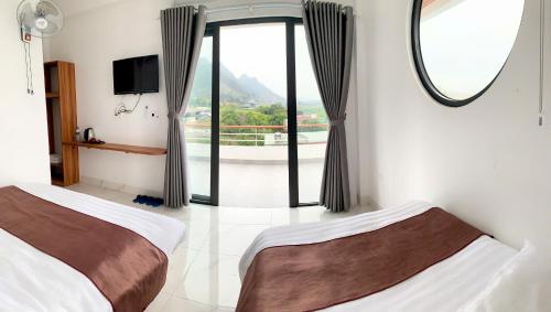 twee bedden in een kamer met een groot raam bij Titanic Mộc Châu in Mộc Châu