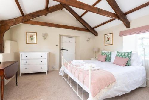 a bedroom with a large white bed and a desk at Hansel Cottage in Dartmouth