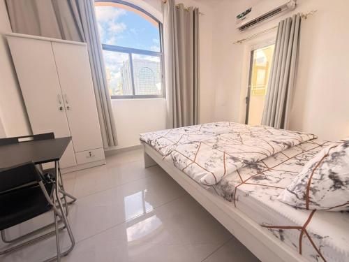 una camera da letto con un letto, una scrivania e una finestra di Flora Residence a Abu Dhabi