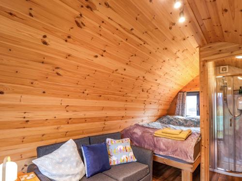 a log cabin bedroom with a bed and a couch at The Pod at Greenbank in Kilbride