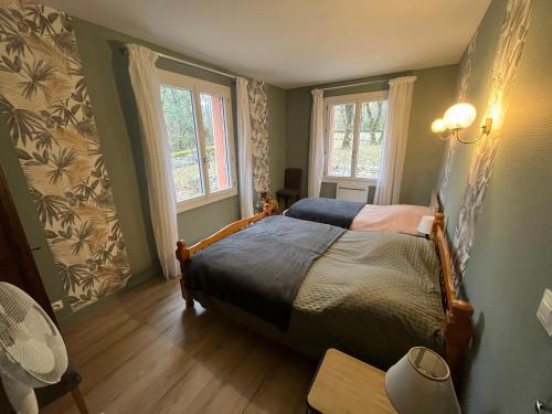 a bedroom with a bed and two windows at La maison dans les bois in Crayssac