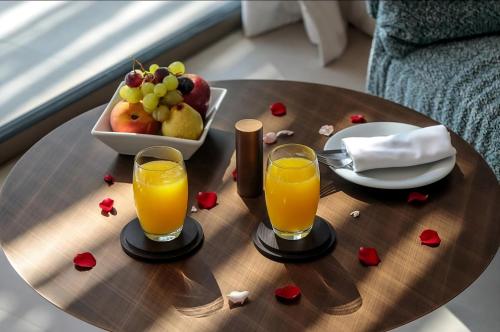 een tafel met twee glazen sinaasappelsap en een fruitschaal bij THE ESTATE - Marrakech in Marrakesh