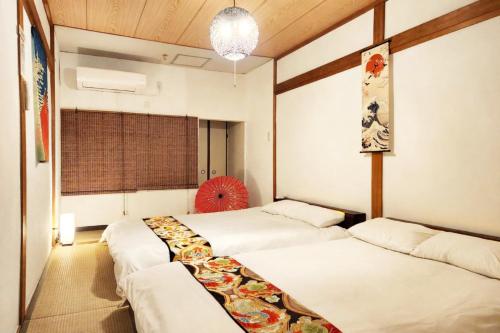 a room with three beds and a window at D,A-House OSAKA in Osaka