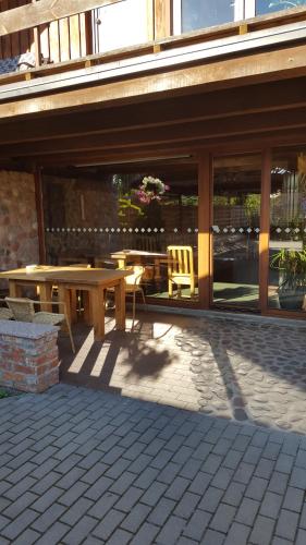 a patio with a wooden table and a table and chairs at Akmenine Kerpe in Marijampolė