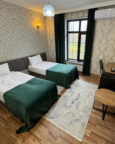 a hotel room with two beds and a table and a desk at Chuxuryurd Hotel in Shamakhi