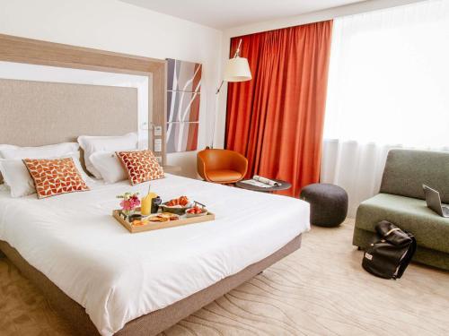 a hotel room with a bed with a tray of food on it at Novotel Lyon Centre-Confluence Bord de Saone in Lyon