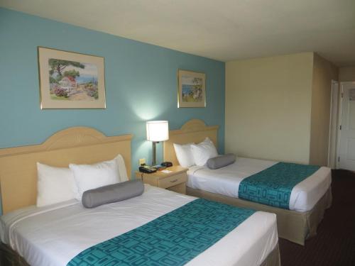two beds in a hotel room with blue walls at Howard Johnson by Wyndham Santa Cruz in Santa Cruz