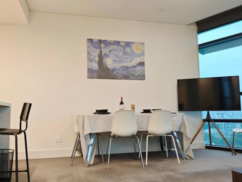 a dining room with a table and chairs and a tv at Above the Park Sydney Harbour City View Stay in Sydney