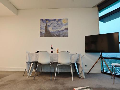 a dining room with a table and a flat screen tv at Above the Park Sydney Harbour City View Stay in Sydney