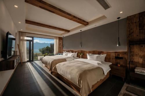 2 Betten in einem Schlafzimmer mit einem großen Fenster in der Unterkunft 慢境Slow Land半山海景花园酒店 in Dali