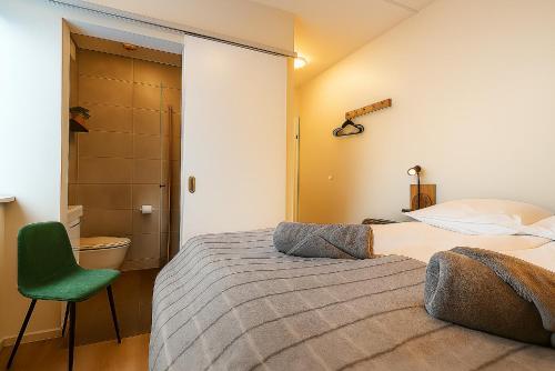 1 dormitorio con 2 camas y silla verde en The Ísafjörður Inn by Ourhotels, en Ísafjörður