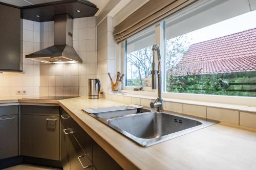 een keuken met een spoelbak en een raam bij Appartementen Ossegang in Uithuizen